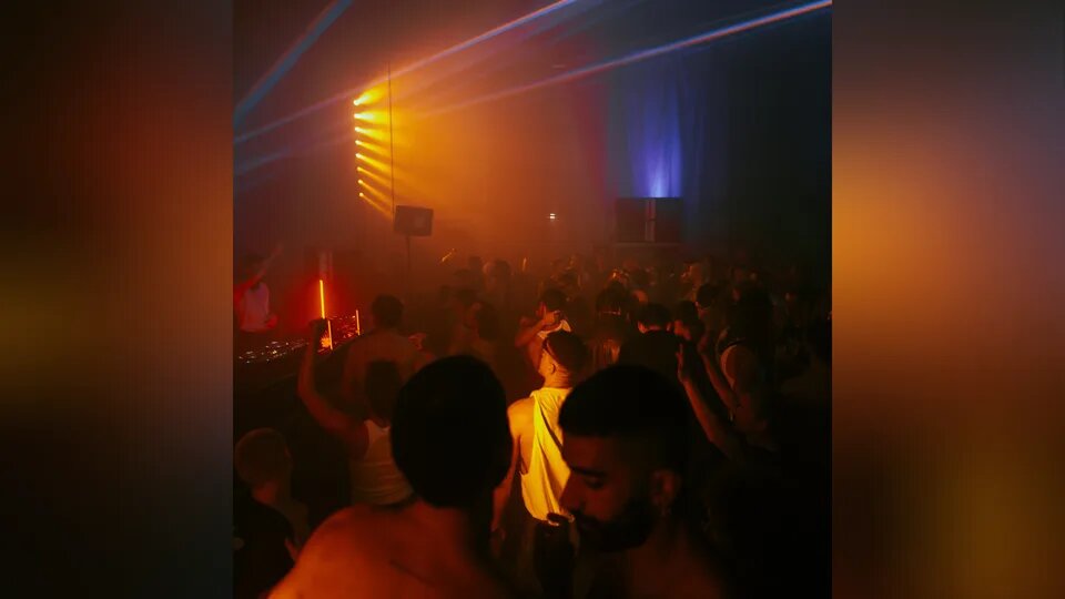 Intimate underground rave with focused crowd close to the DJ booth and dramatic dark lighting, representing curated identity events